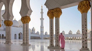 Scheich-Zayid-Moschee in Abu Dhabi Eine Frau in einem Gewand steht an einer Säule einer weißen Moschee in Abu Dhabi