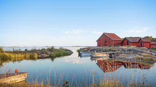 Skandinavisches Haus mit Booten am Steg umgeben von Wasser Skandinavisches Idyll