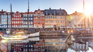 Nyhavn in Kopenhagen bei Sonnenaufgang Segelboote liegen im Hafen von Kopenhagen vor Anker während die Sonne hinter den Häusern aufgeht