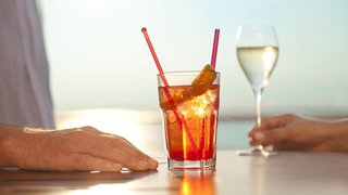 Zwei Getränke stehen auf einem Tisch man sieht die Hände von zwei Personen