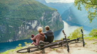 Ehepaar sitzt am Fjord neben ihren Fahrrädern