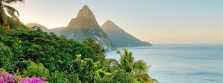 Blick auf die grüne Küste von St. Lucia mit einem Sonnenaufgang hinter den Bergen