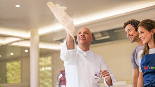 Ein Koch schleudert Pizzateig in die Luft