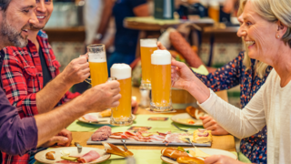 Gruppenreisen mit AIDA Gruppe sitzt im Restaurant und stößt mit Bier an