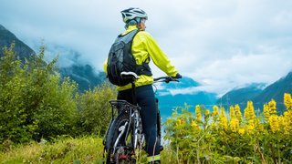 Frau steht auf einem Berg mit Fahhrad