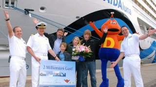 2 Millionster Gast auf AIDA AIDA Offiziere und Dodo überreichen dem 2 Millionsten Gast Blumen und einen Gutschein