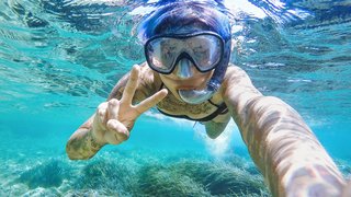 Eine Frau mit Taucherbrille und Schnorcheln fotografiert sich unter Wasser