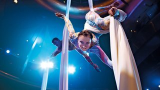 Artistin performt an Tüchern die von der Decke im Theatrium hängen