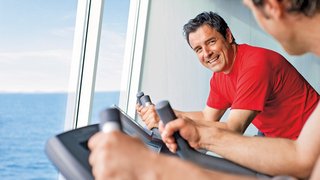 Zwei Männer trainieren auf Fitnessgeräten mit Meerblick
